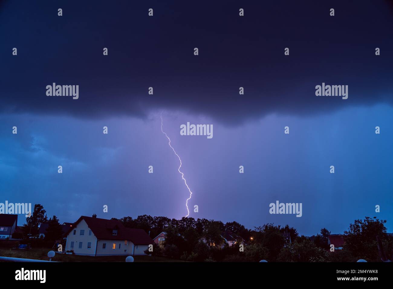 A dark purple sky with striking lightning over a city Stock Photo - Alamy