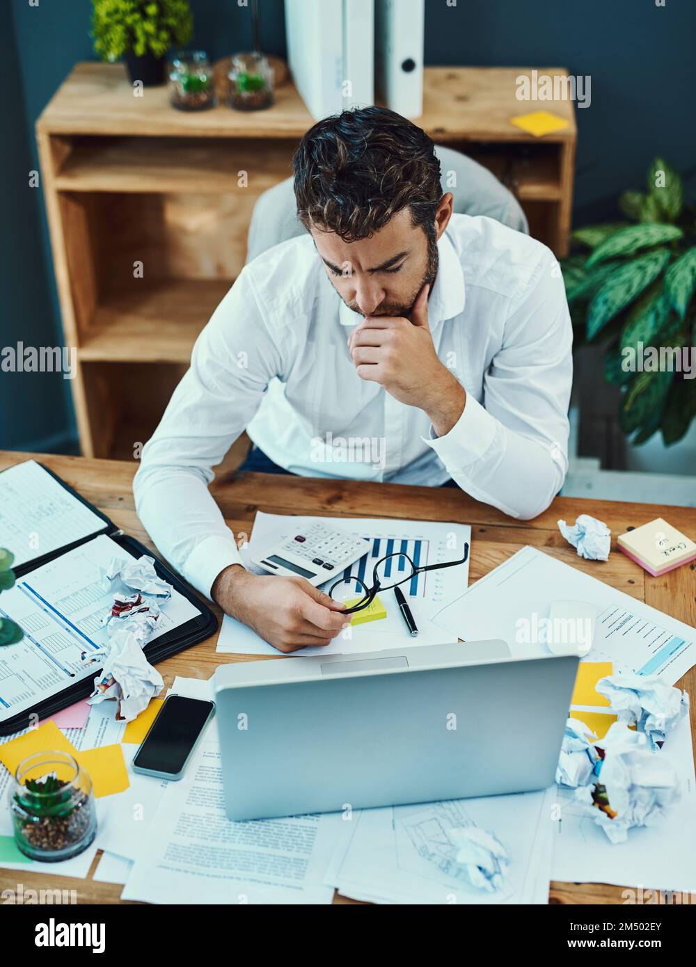 Some problems take longer to tackle. a young businessman looking serious while working on a laptop in an office. Stock Photo