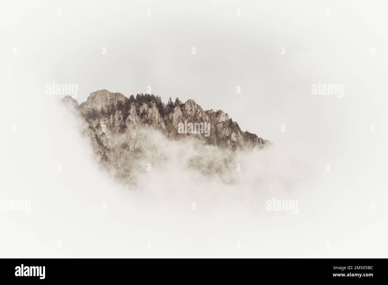 A scenic view of a rocky mountain peak covered with dense fog in ...