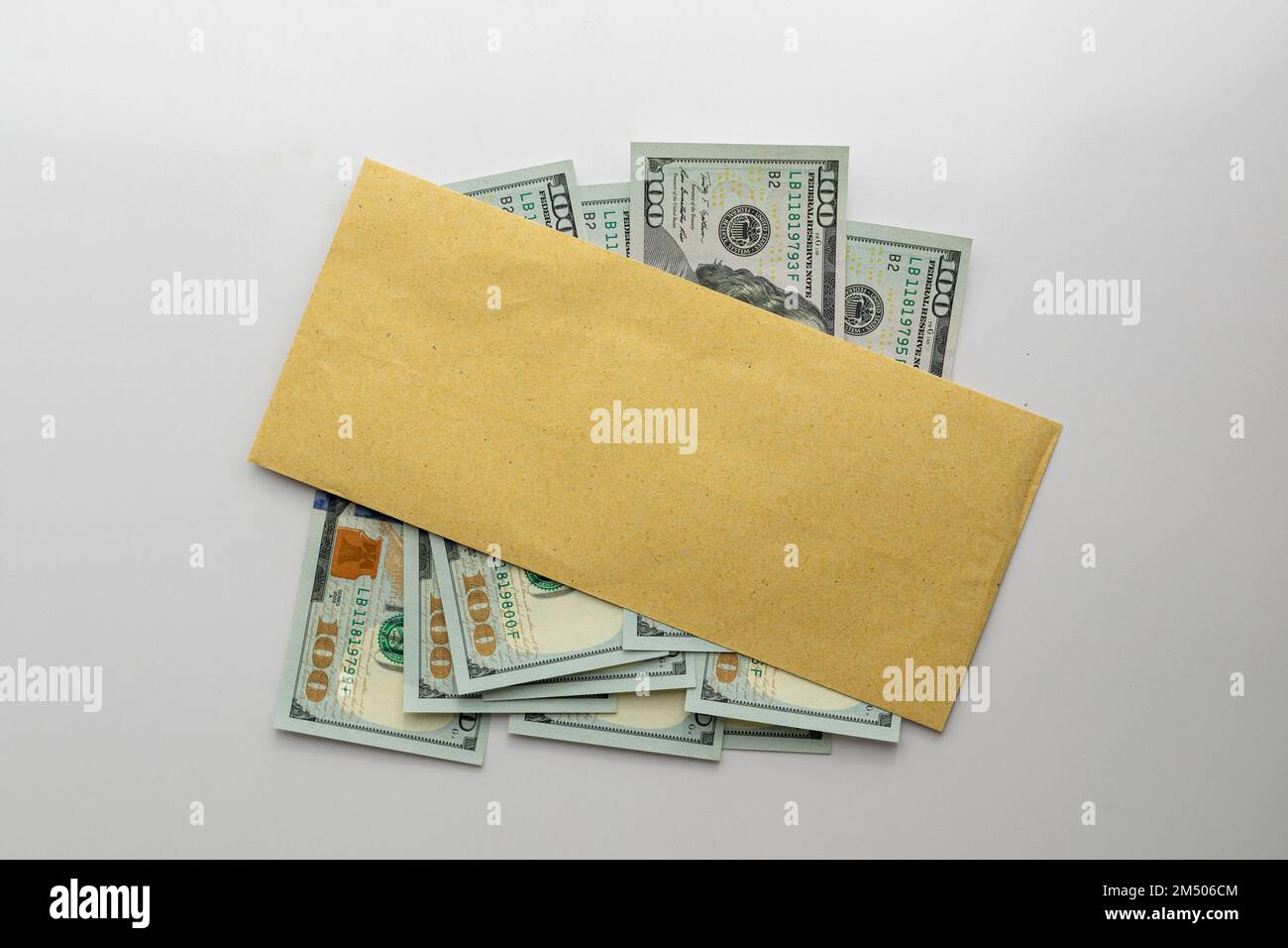 Blank brown envelope over a new US dollars banknotes isolated on white