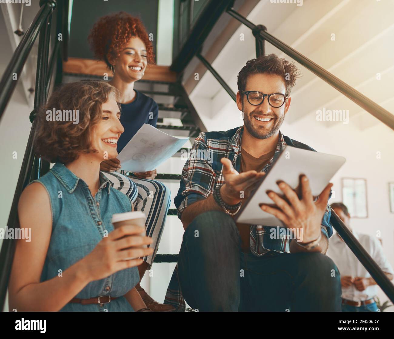 Creativity is always better shared. creative employees having a discussion on the staircase at work. Stock Photo