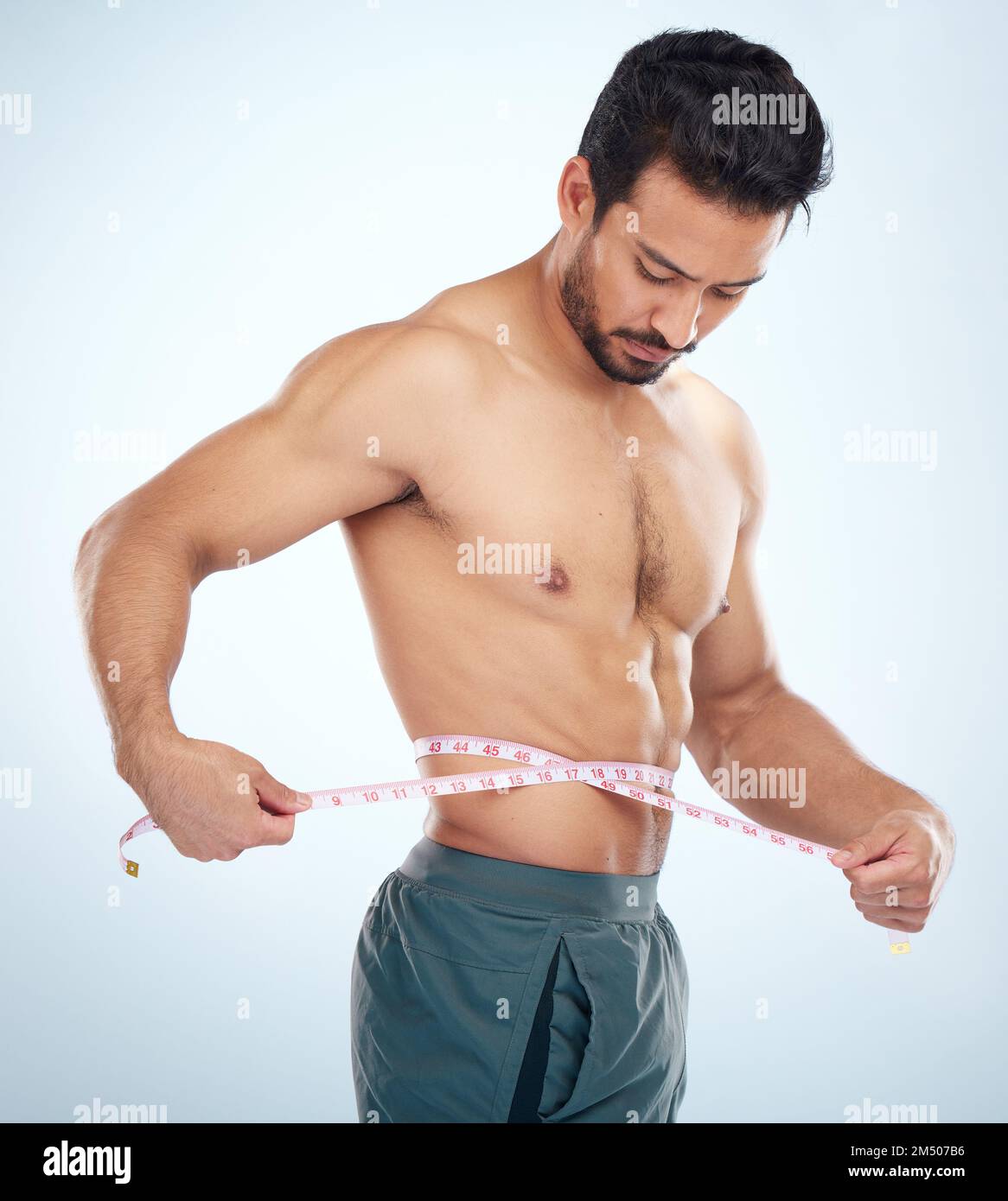 Man, body or measuring tape on waist on studio background for weight loss management, fat control or bmi and diet wellness. Fitness model, sports Stock Photo