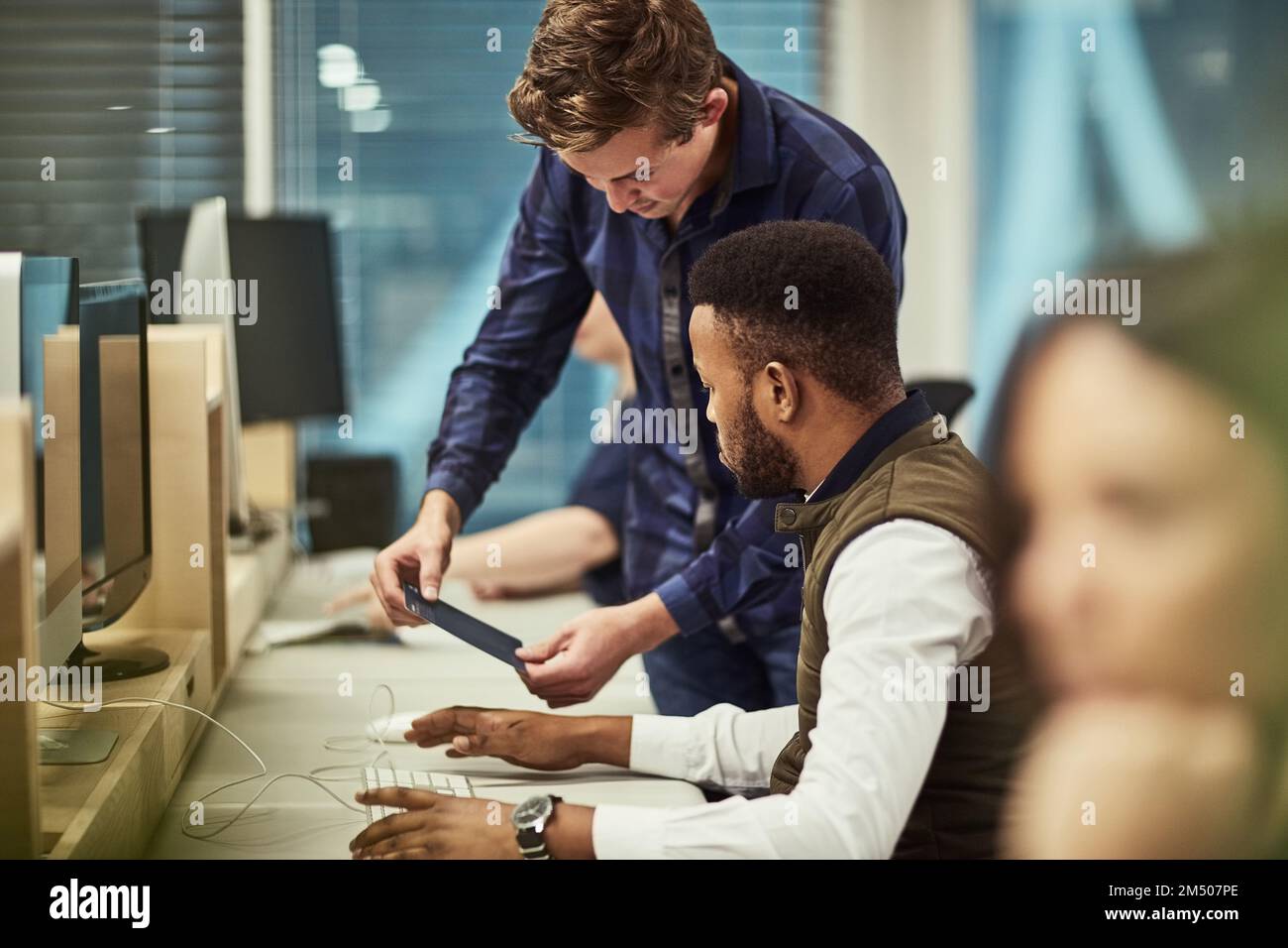 Aiming to achieve the exceptional together. a group of designers working on computers in an office. Stock Photo