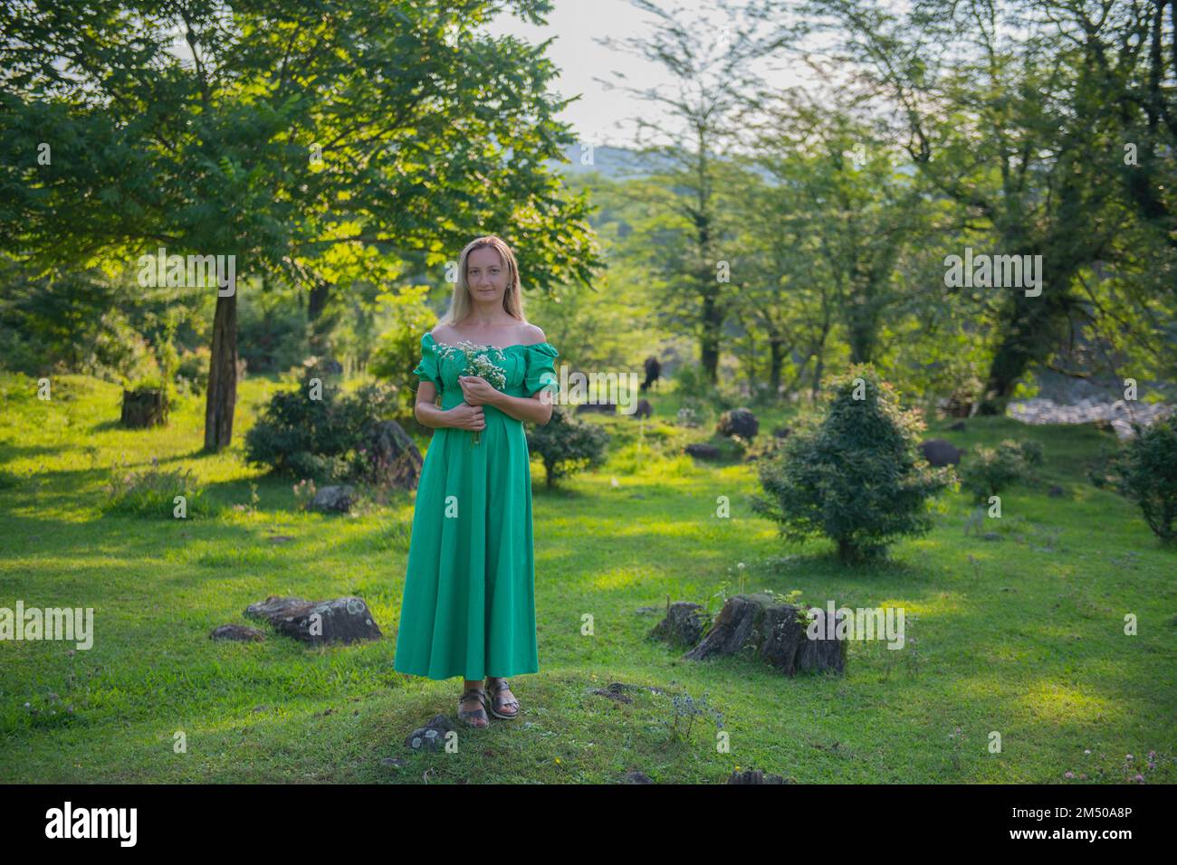 a woman in a green dress with flowers in a clearing Stock Photo - Alamy