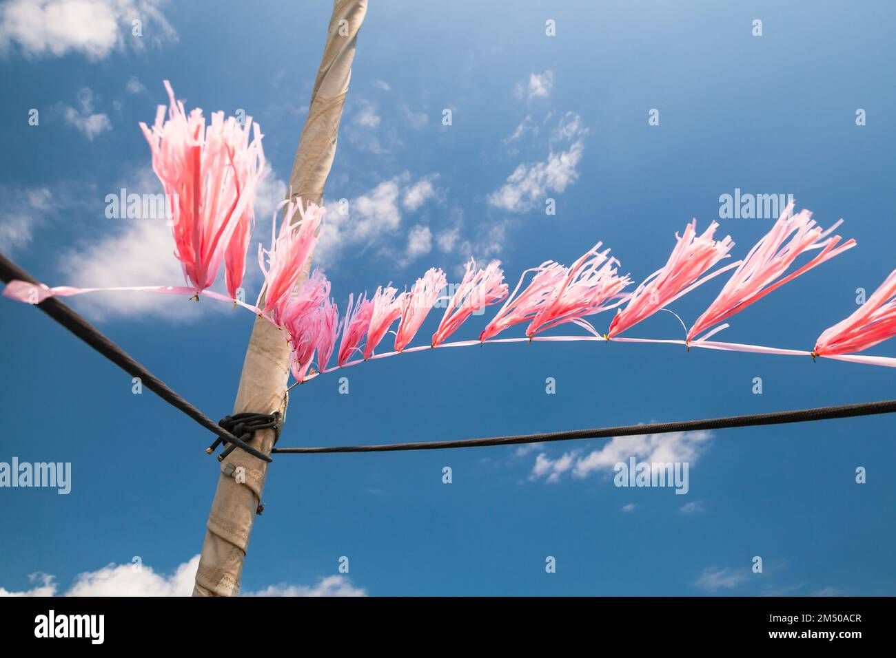 Pink decoration hangs on a yacht  mast under blue sky on a sunny day Stock Photo