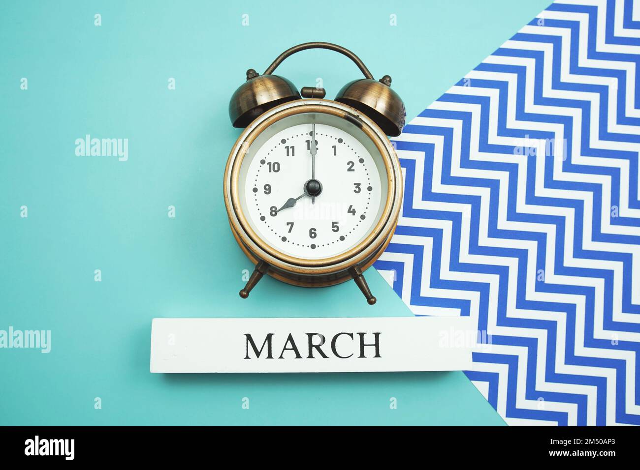 March and alarm clock on blue background Stock Photo - Alamy
