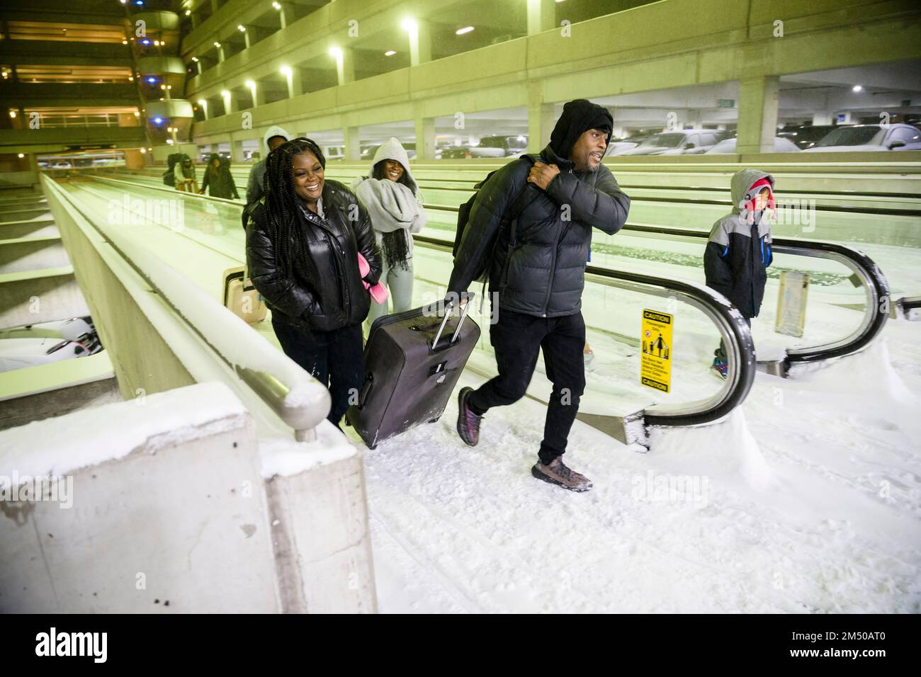 Columbus, Ohio, USA. 23rd Dec, 2022. Travelers talk along a snowed-over and frozen walkway in the parking garage of John Glenn Columbus International Airport in Columbus, Ohio as a major winter storm brings subzero temperatures across the United States. Credit: ZUMA Press, Inc./Alamy Live News Stock Photo