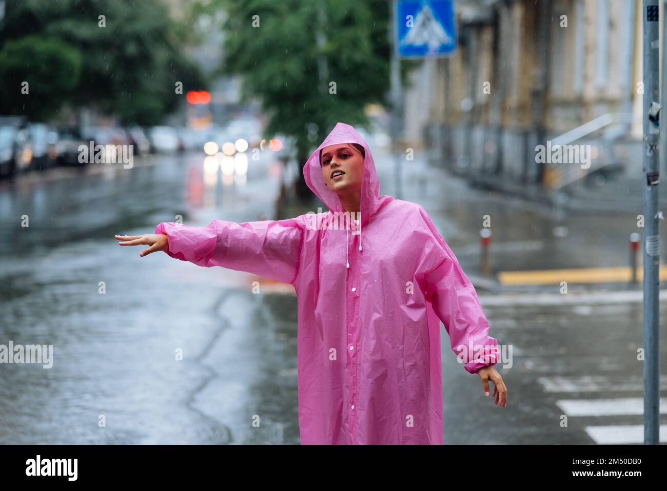 Young girl trying to stop a cab. Woman calling a taxi on a rainy day. Stock Photo