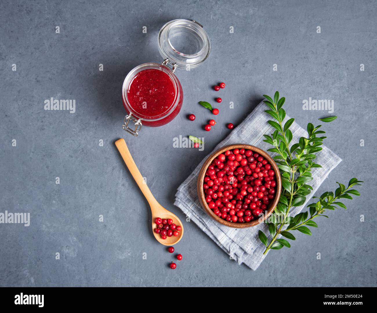 juicy forest lingonberry with handmade jam  in a jar on gray background. Concept homemade healthy food. Top view and copy space image Stock Photo