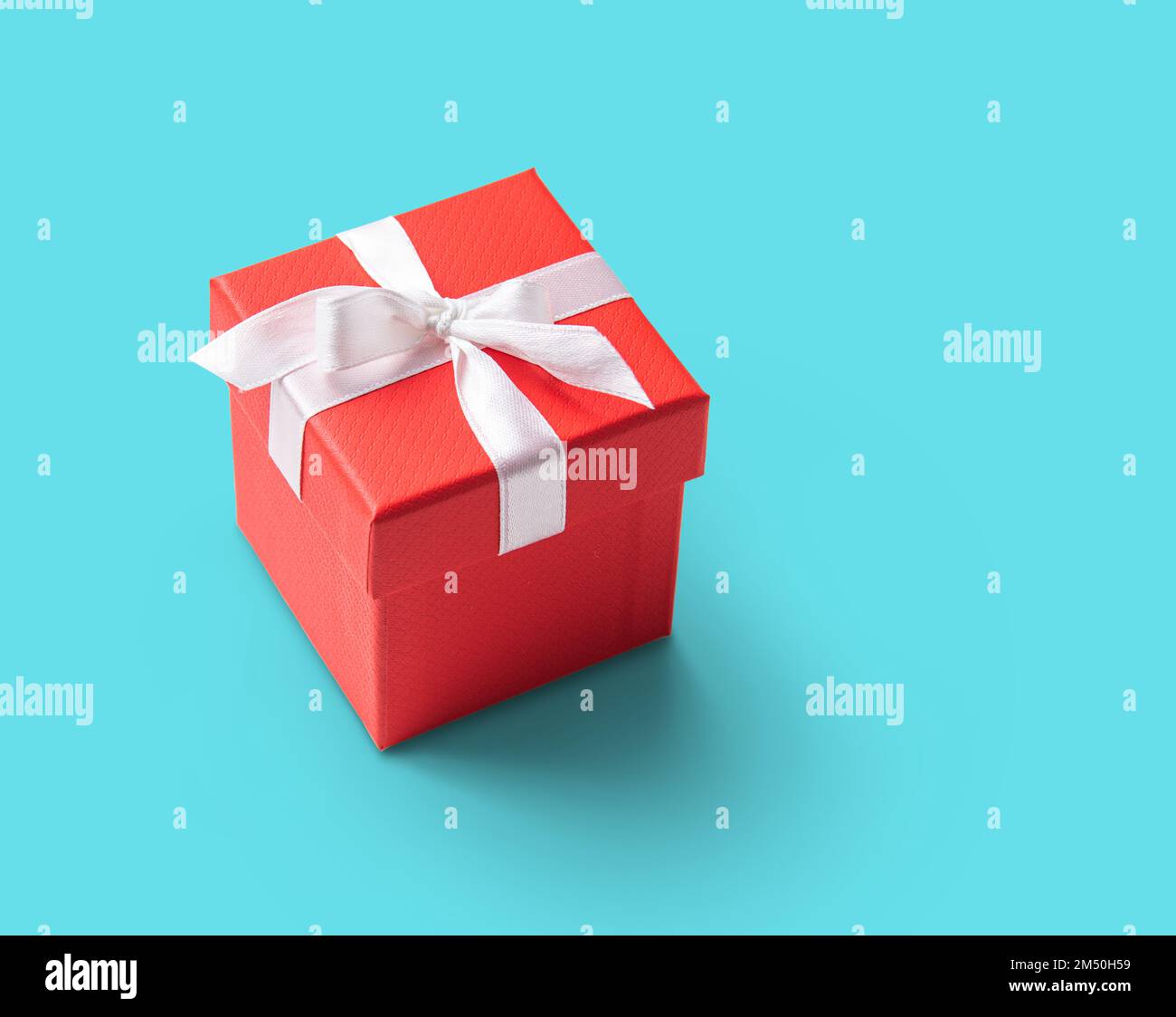 red present box with white ribbon on  blue background. Concept and celebration photo. Copy space Stock Photo