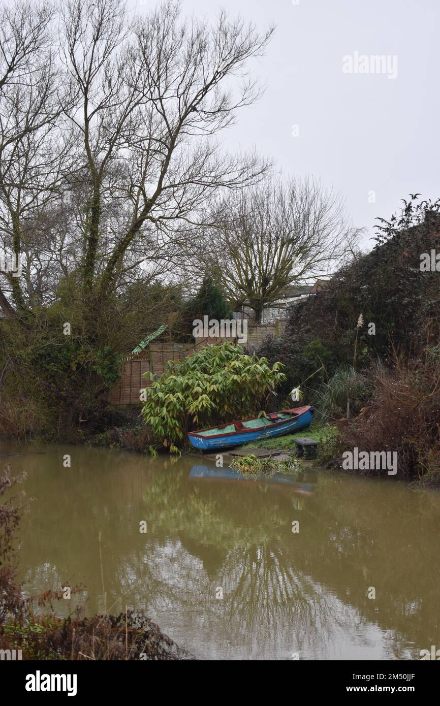 Rowing boat in a garden backing onto the river. Stock Photo
