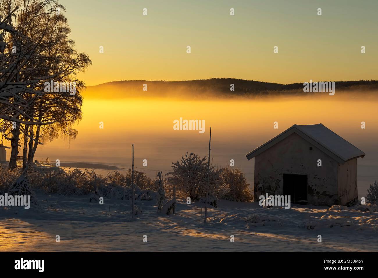 Sunset over lake Bysjön in Grangärde Sweden with mist covering the ice on the lake Stock Photo