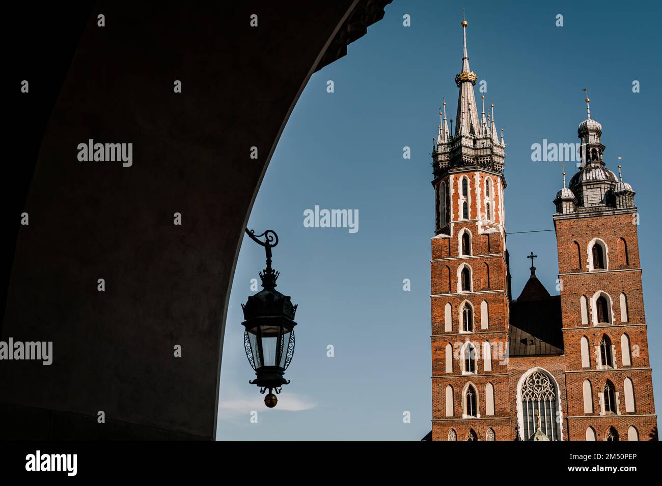 St. Mary's Basilica at Market Square in the Old Town of Krakow, Poland. View through archway with lantern. Stock Photo