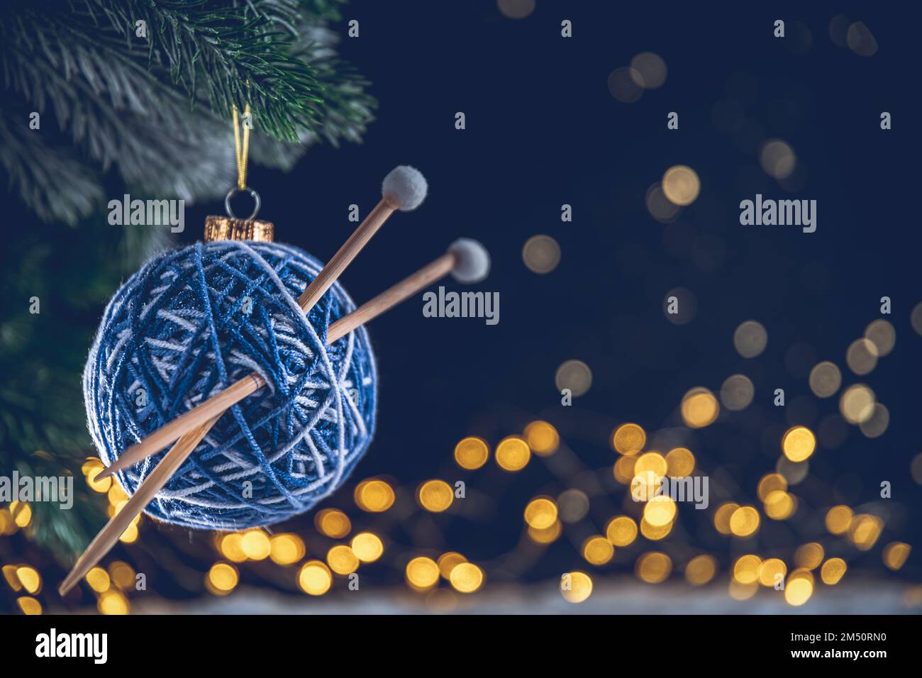 blue Christmas ball in the form of a ball of threads with spokes on the Christmas tree. needlework. with copy space Stock Photo