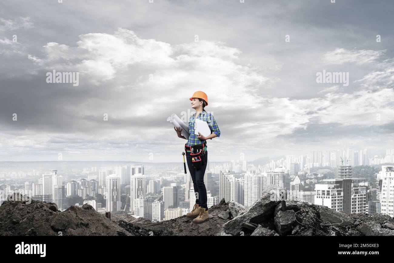 Female engineer in hardhat standing with blueprint Stock Photo - Alamy