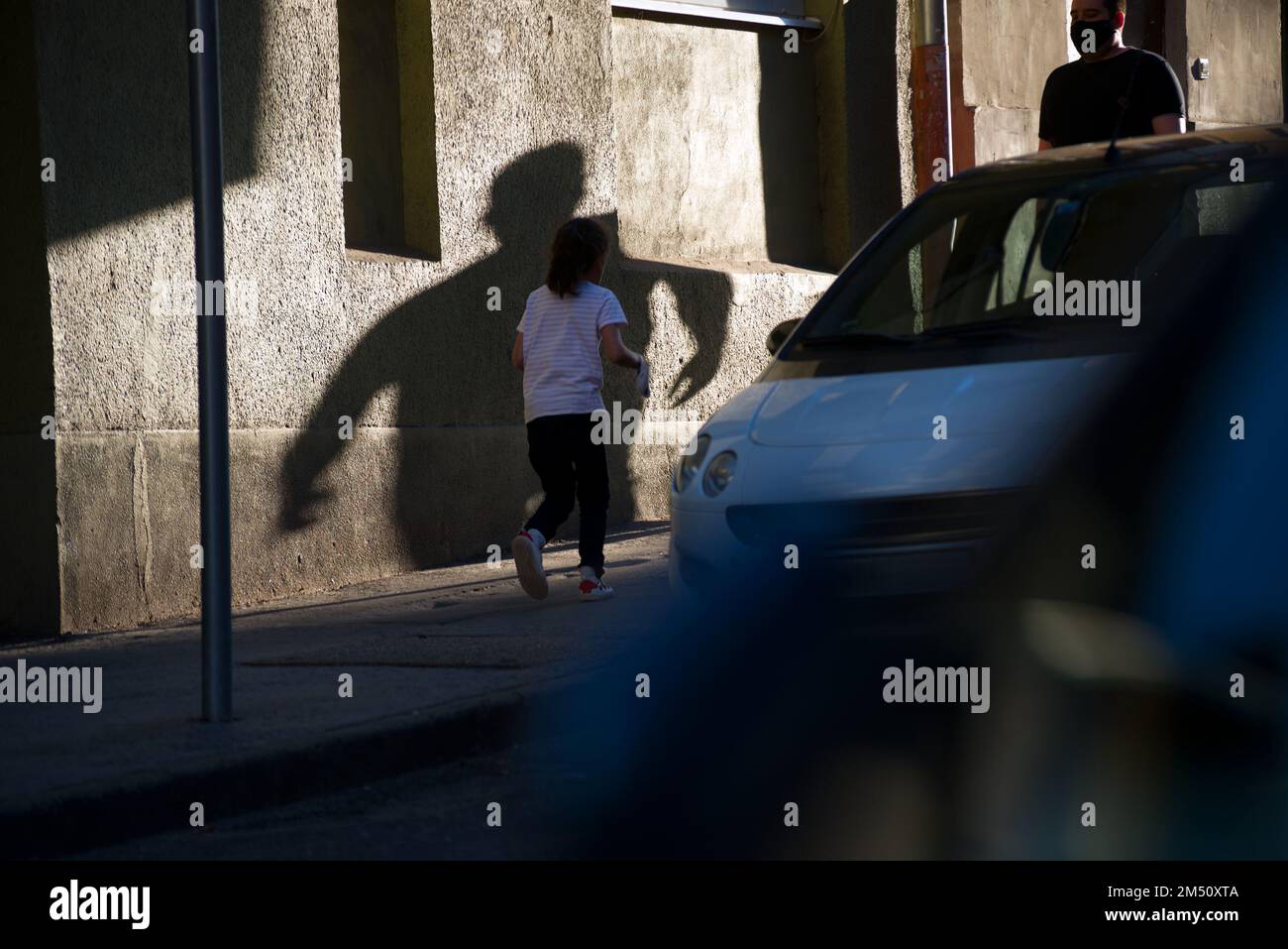 Child and stranger's frightening shadow on a street Stock Photo