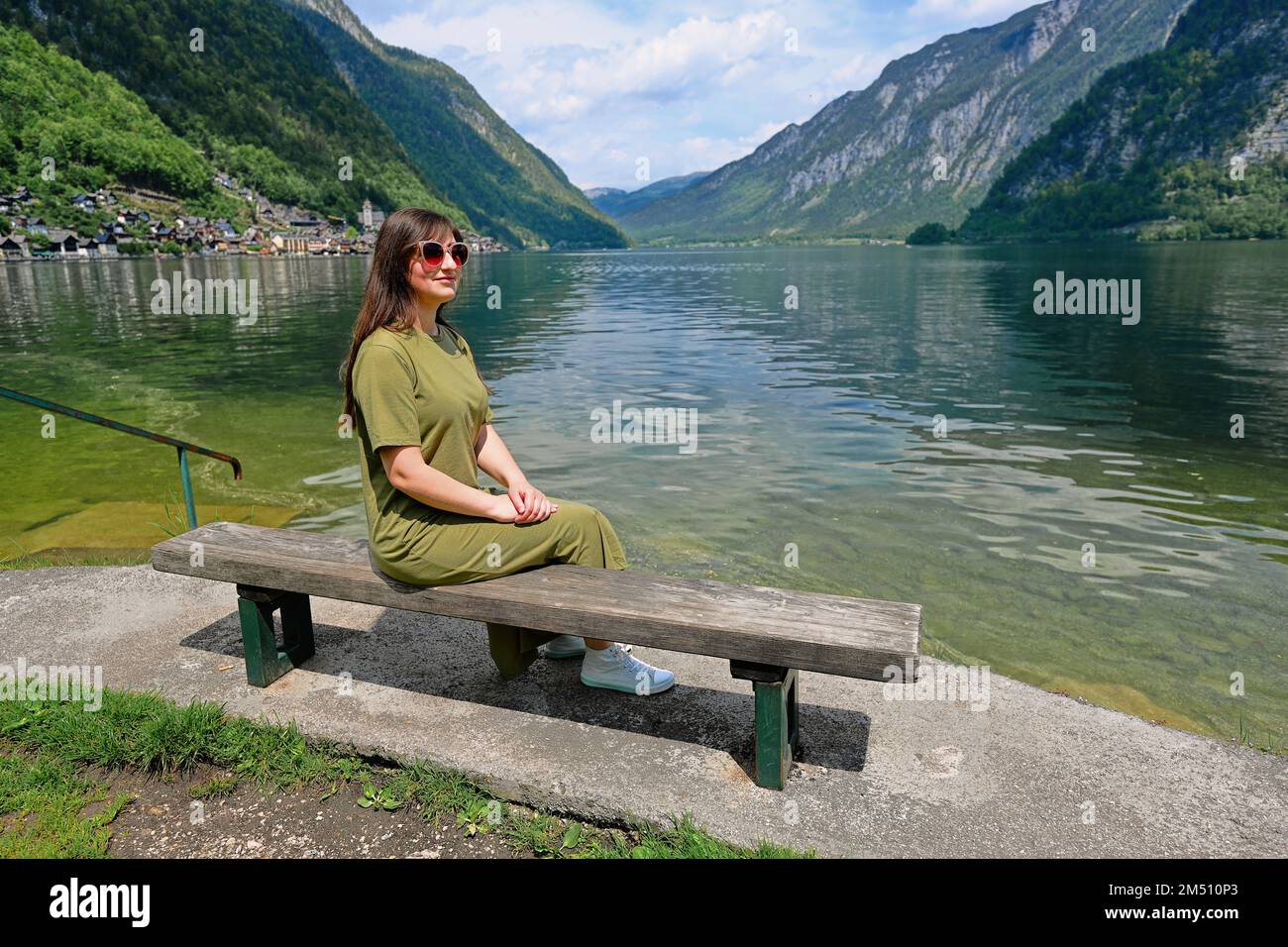 Woman sit in bench over Austrian alps lake in Hallstatt, Salzkammergut, Austria. Stock Photo