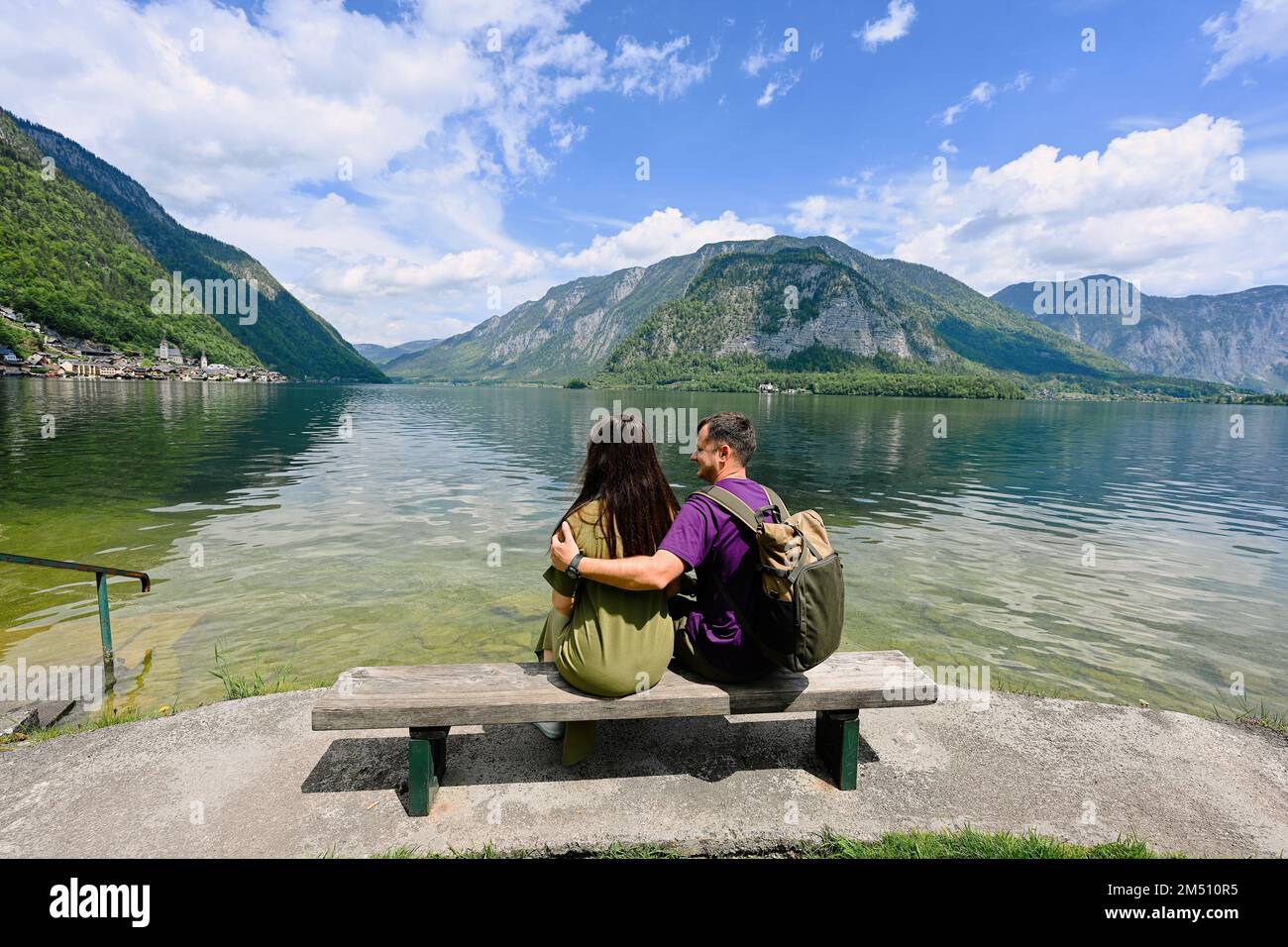 Couple sitting on bench over Austrian alps lake in Hallstatt, Salzkammergut, Austria. Stock Photo