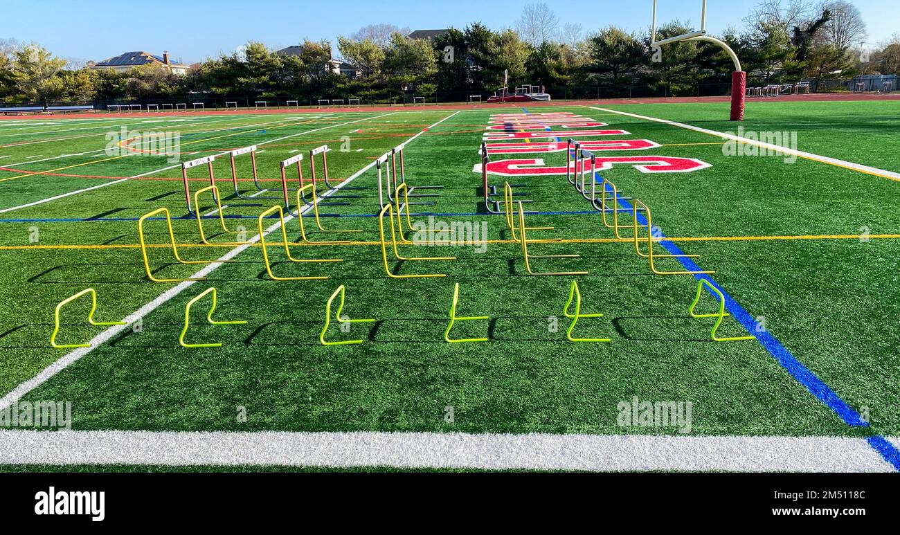 Different sized hurdles set up on turf field for stength and agility practice for a high school