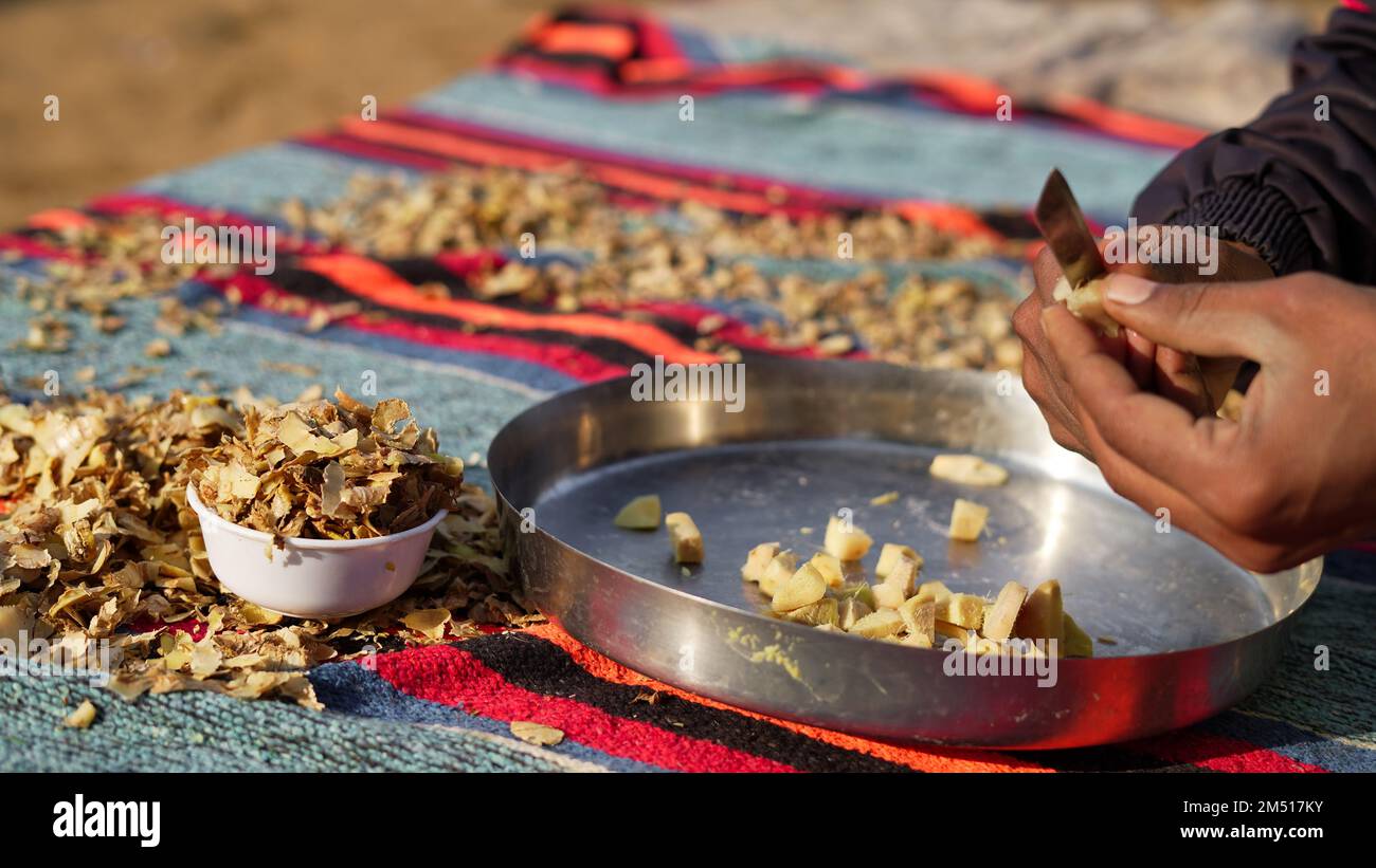 A pile of Ginger roots peeled with knife over chopping block. Ginger or ...