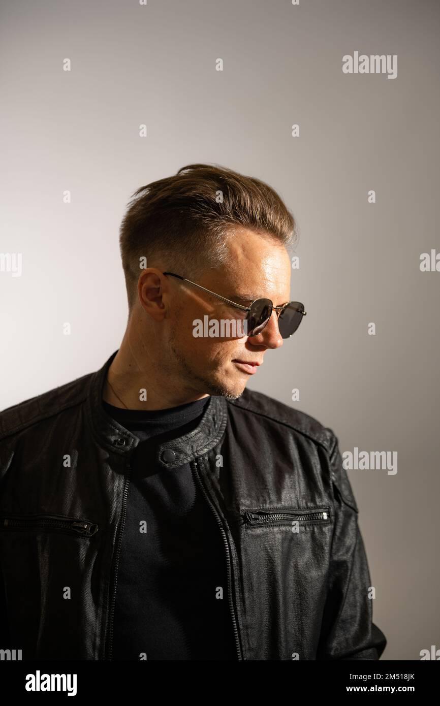 Portrait of handsome male. Sexy stylish man dressed in a leather jacket and sunglasses. Fashion hipster male isolated on white background in studio Stock Photo