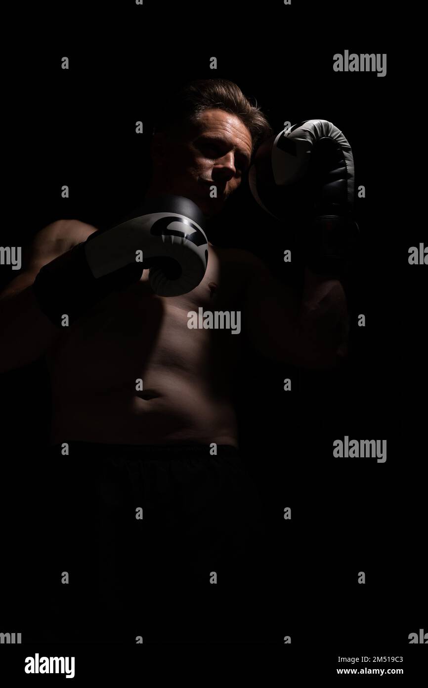 Portrait of muscular handsome topless male wearing boxing gloves isolated against a black background Stock Photo