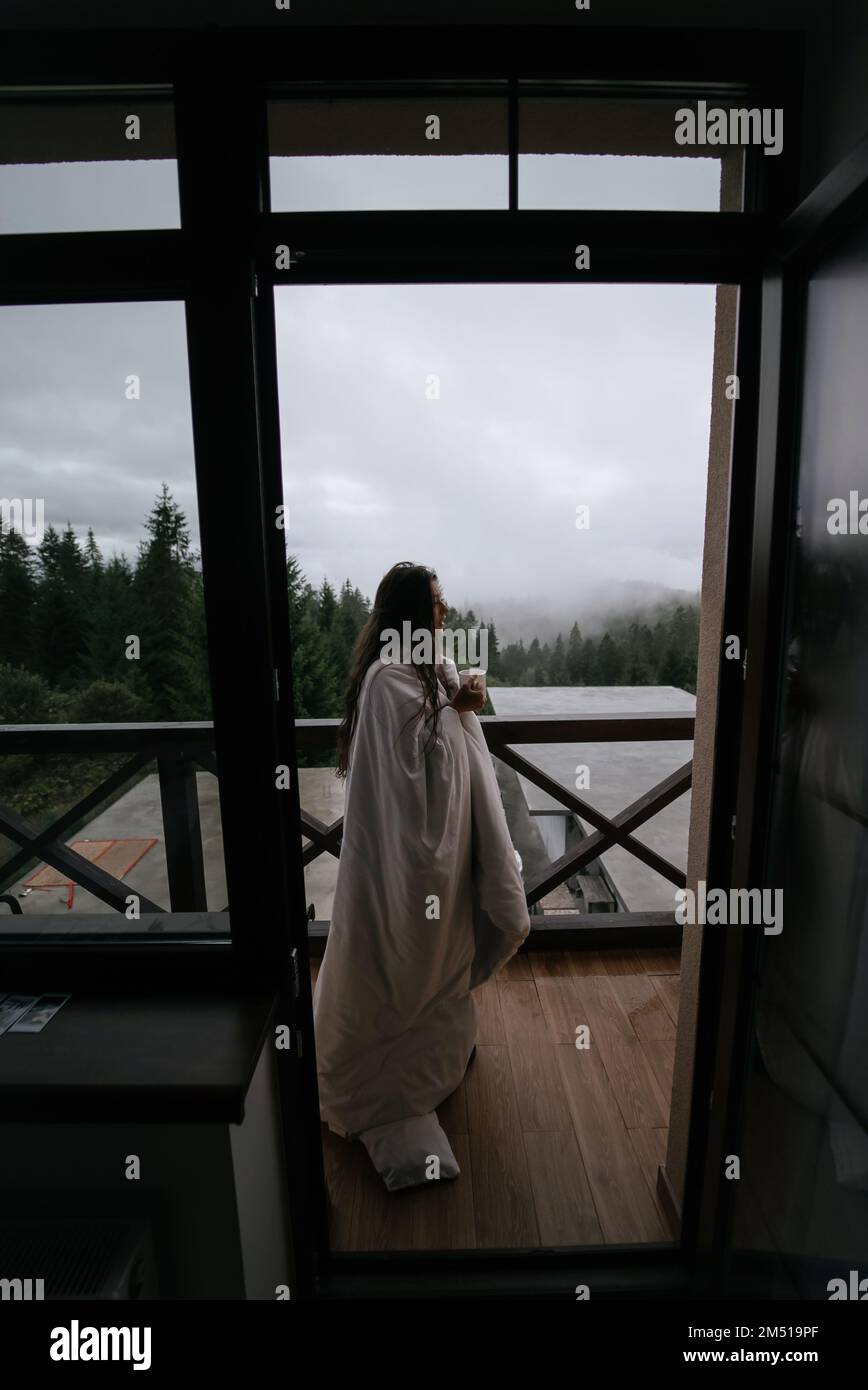 Woman drinking tea on cozy balcony of a country house. Stock Photo