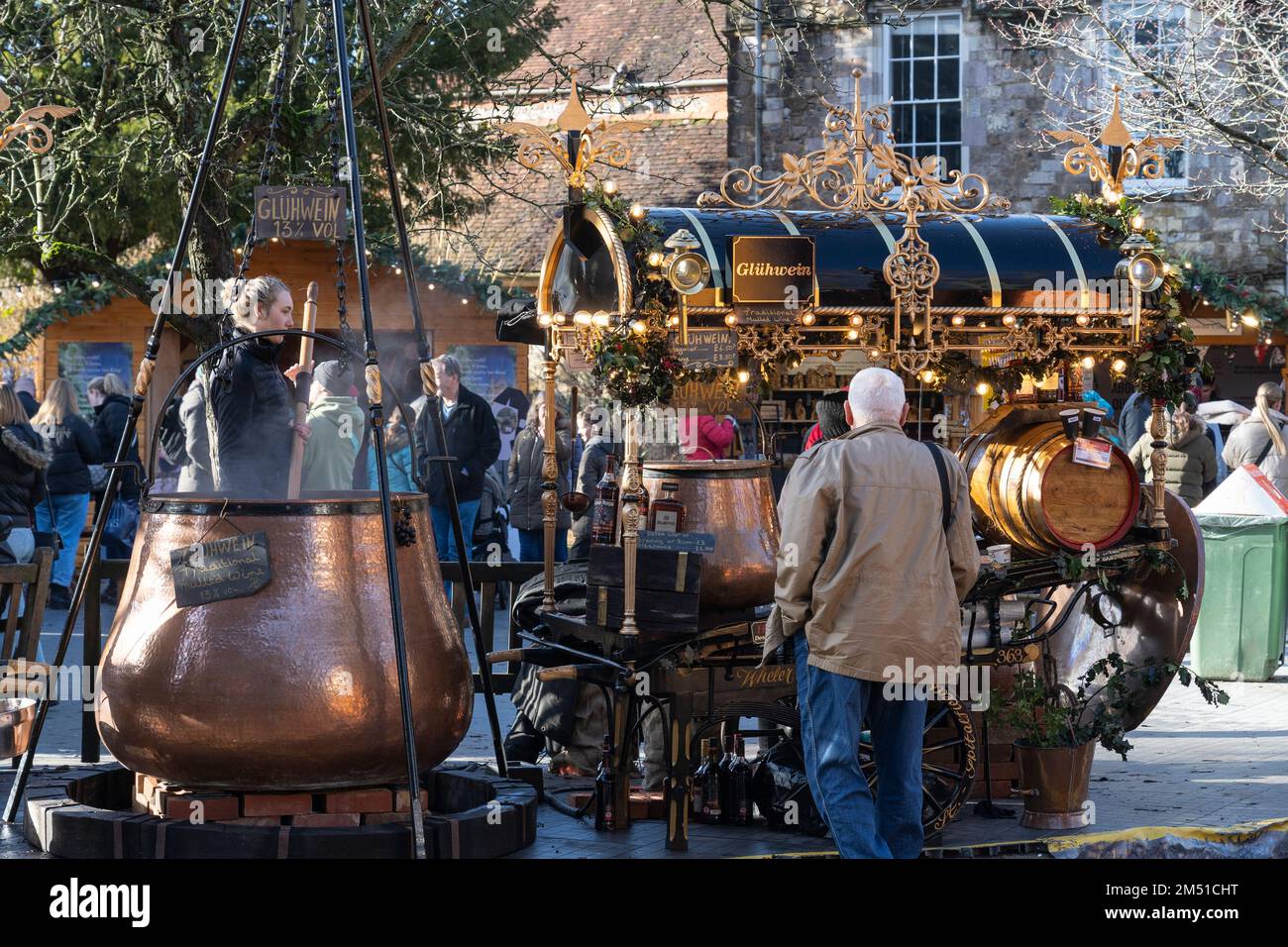 Traditional Glühwein (mulled wine) stand at Winchester Christmas market with a large copper stirring cauldron. At gothic Winchester Cathedral, England Stock Photo