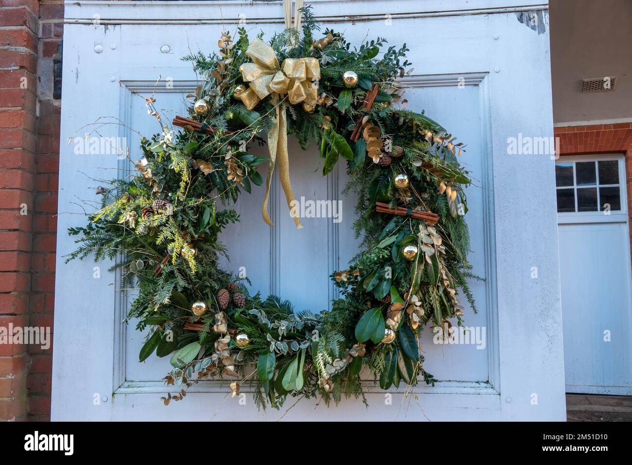 christmas wreath on door with gold ribbon baubles and cinnamon sticks