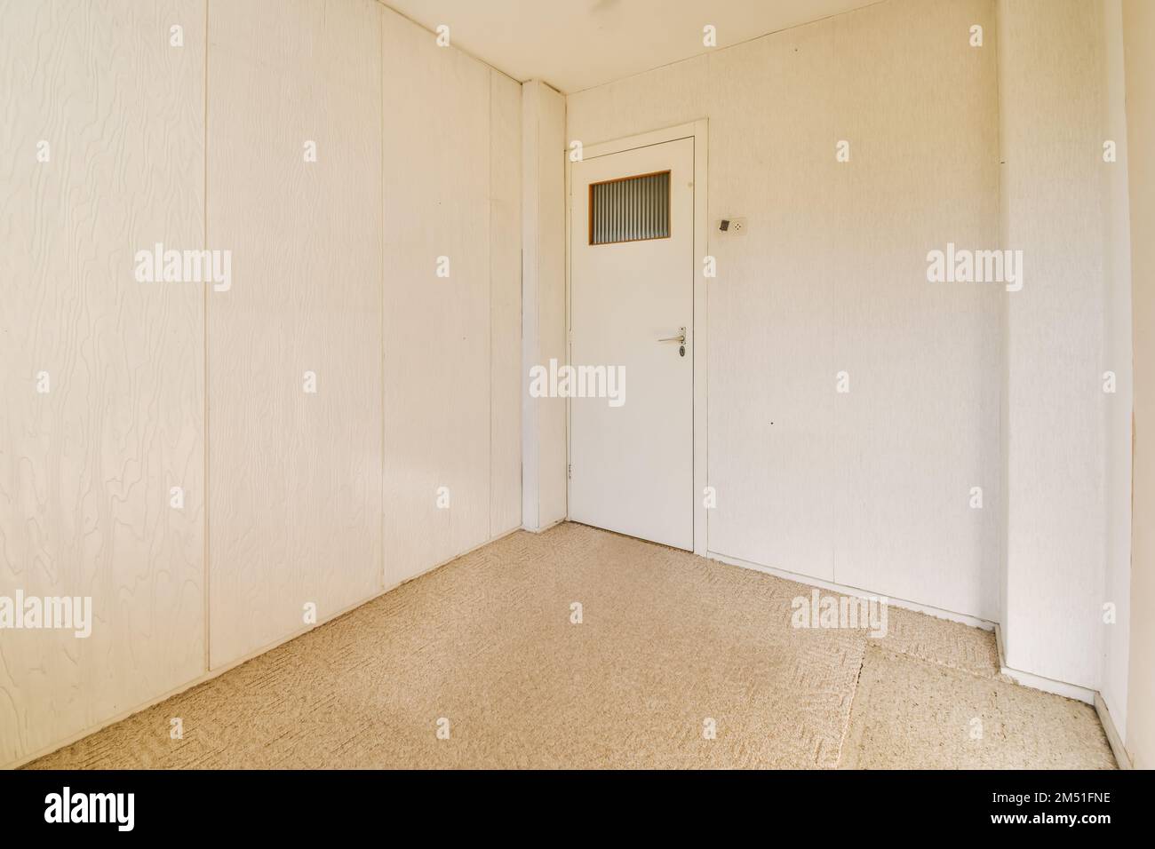 an empty room with white walls and wood paneled doors on either side of the room, one door is open Stock Photo