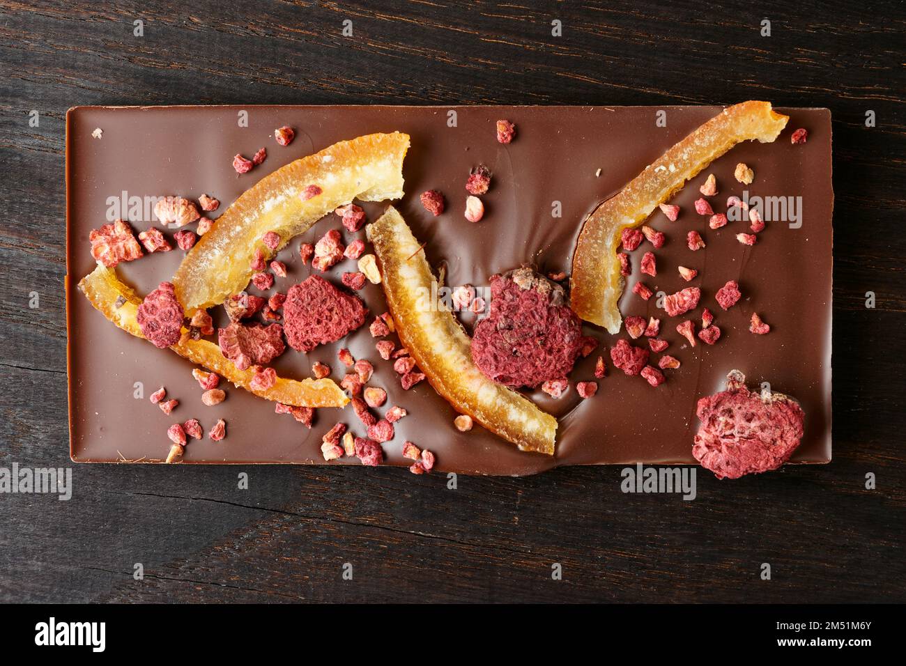 Chocolate bar with candied orange peel and raspberry on dark wood ...