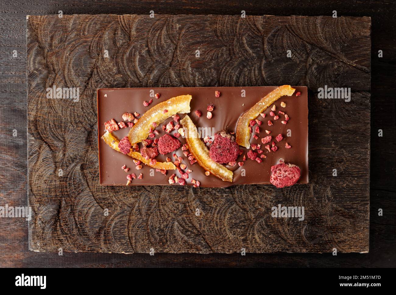 Chocolate bar with candied orange peel and raspberry on dark wood ...