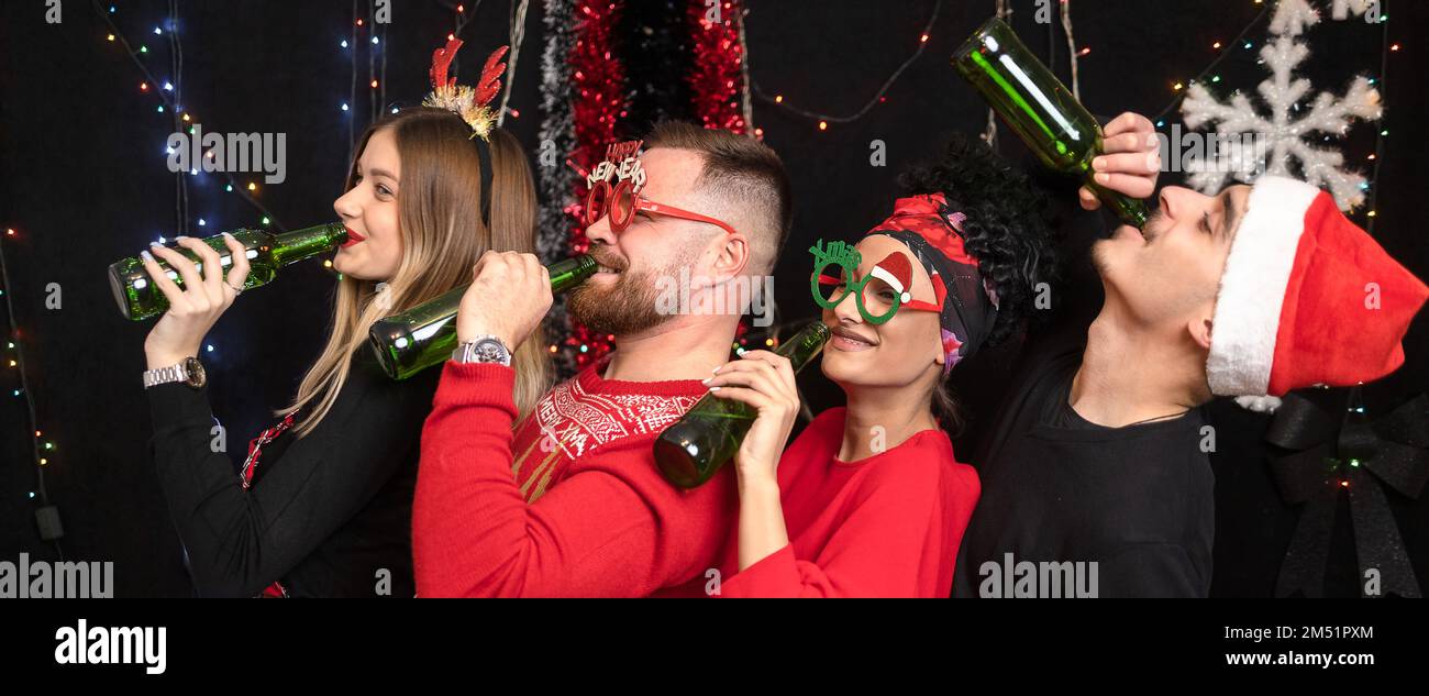 Four friends leaning backwards in a row, drinking beer. New year celebration Stock Photo