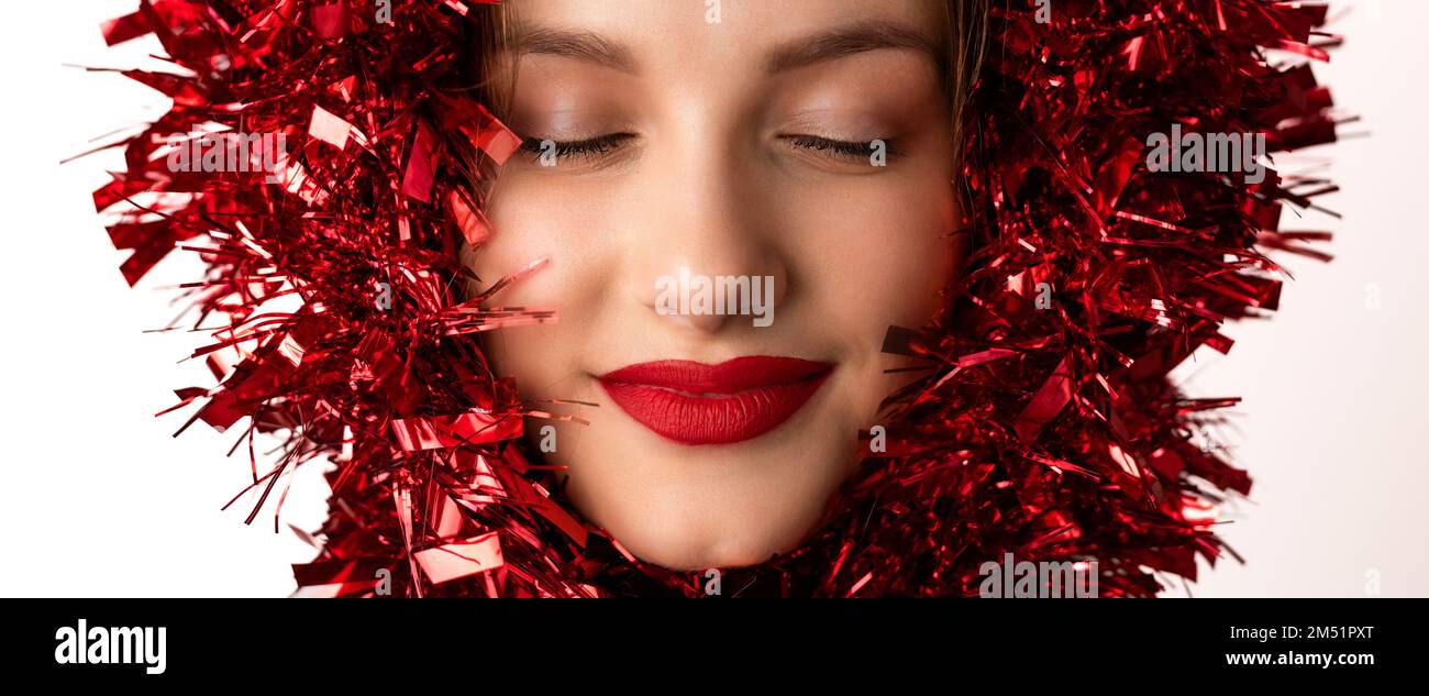 Young, pretty, blonde woman with red garland decoration over her head, closed eyes. Banner, wide format Stock Photo