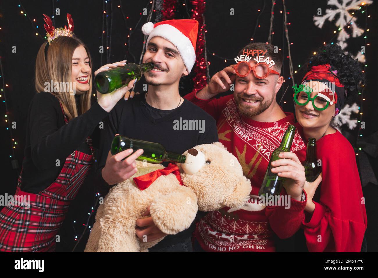 Four friends celebrating New year toasting with beer bottles. Stock Photo