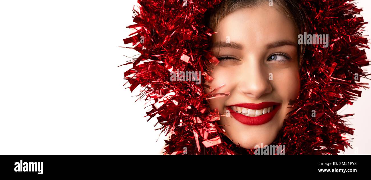 Young, pretty, blonde woman with red garland decoration over her head winking. Banner, wide format Stock Photo