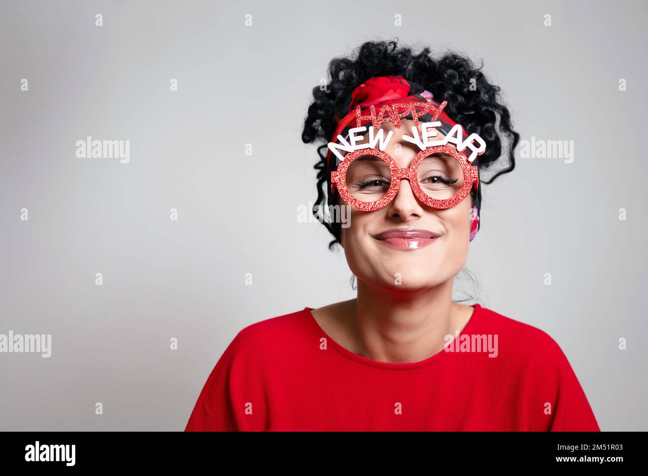Beautiful curly young girl with New year prop glasses and bandana hairstyle Stock Photo