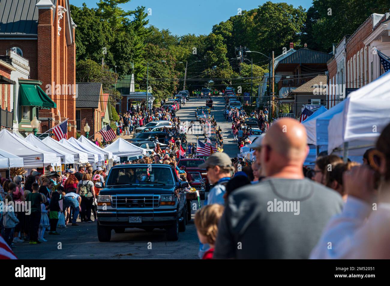 A Small town Applefest parade with crowd and booths lining the route