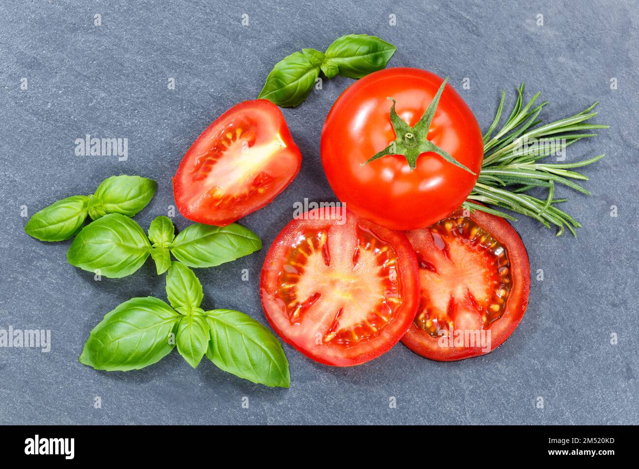 Tomatoes tomatos vegetables with basil from above on a slate from above Stock Photo