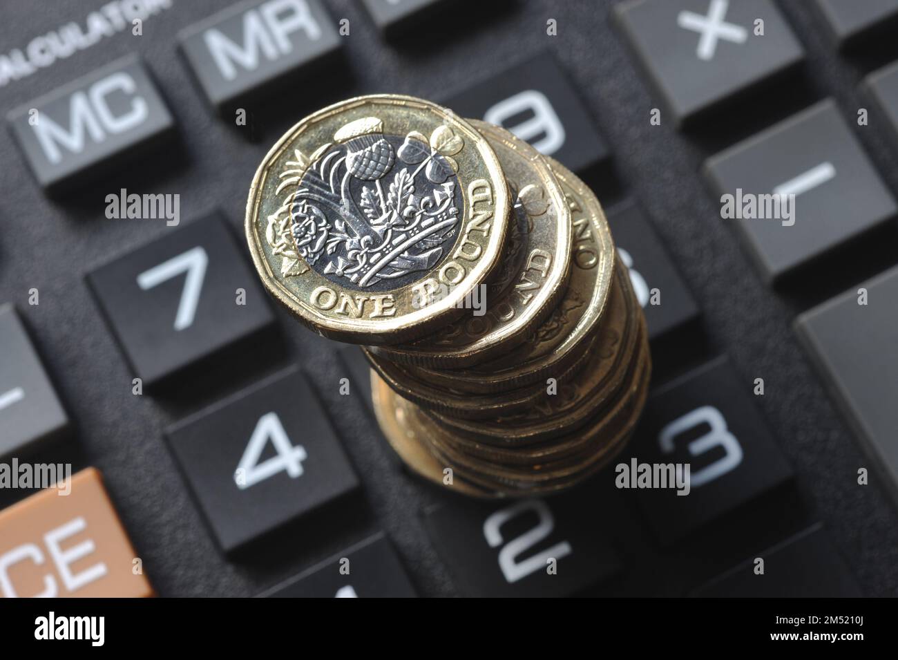 STACK OF ONE POUND COINS ON CALCULATOR RE COST OF LIVING CRISIS PENSIONS INCOME INFLATION HOUSEHOLD BUDGETS ETC UK Stock Photo