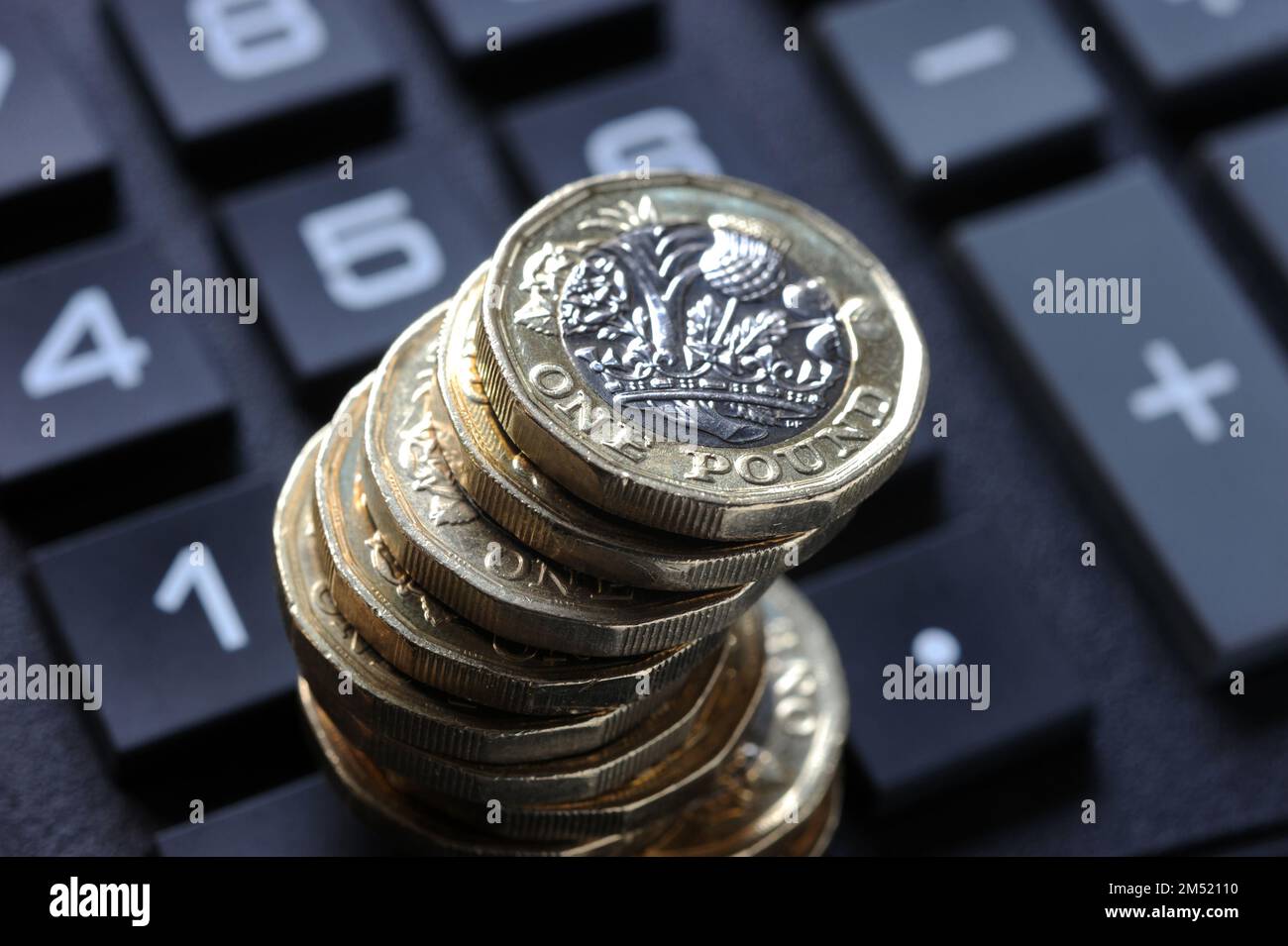 STACK OF ONE POUND COINS ON CALCULATOR RE COST OF LIVING CRISIS PENSIONS INCOME INFLATION HOUSEHOLD BUDGETS ETC UK Stock Photo