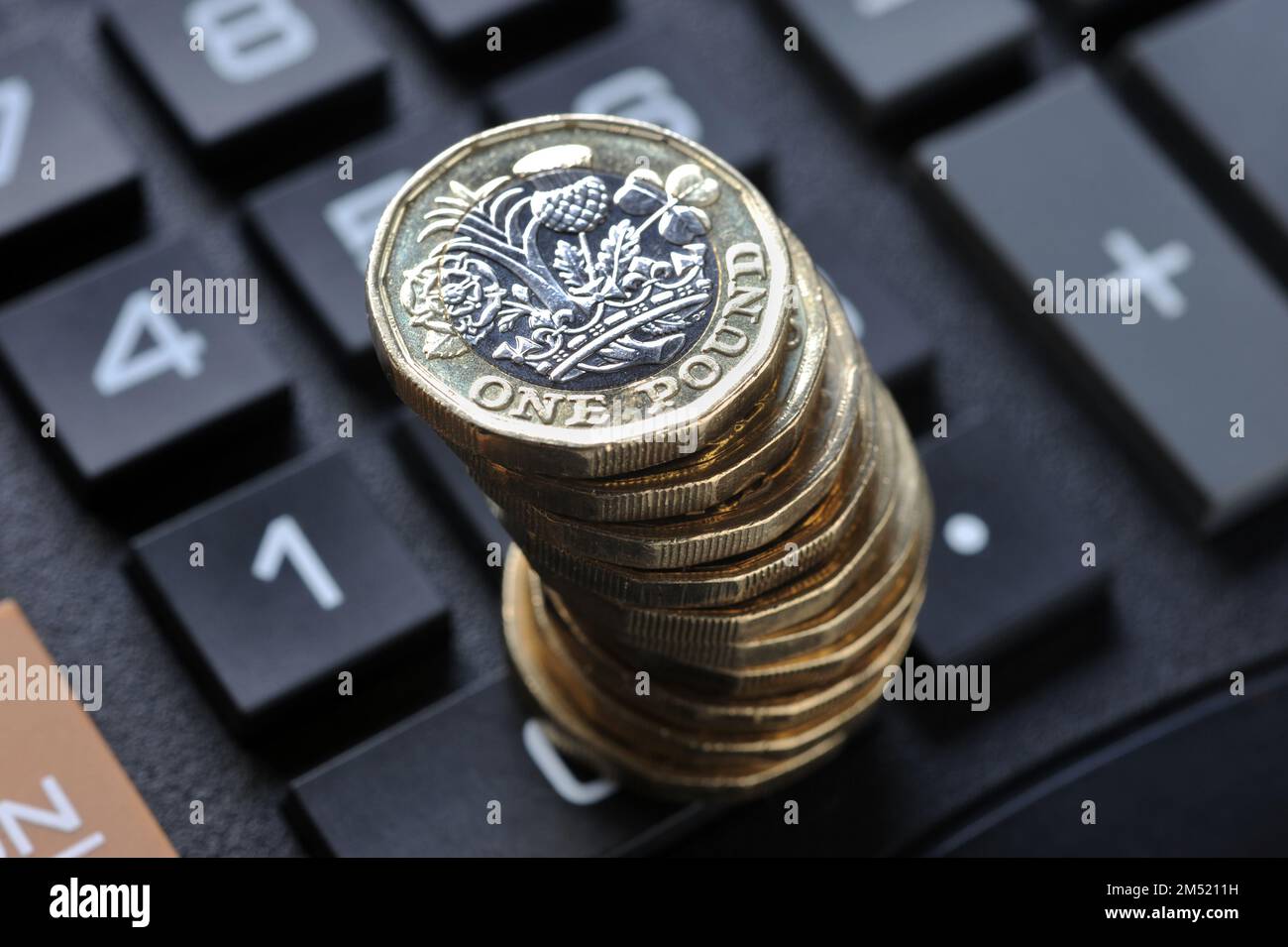 STACK OF ONE POUND COINS ON CALCULATOR RE COST OF LIVING CRISIS PENSIONS INCOME INFLATION HOUSEHOLD BUDGETS ETC UK Stock Photo