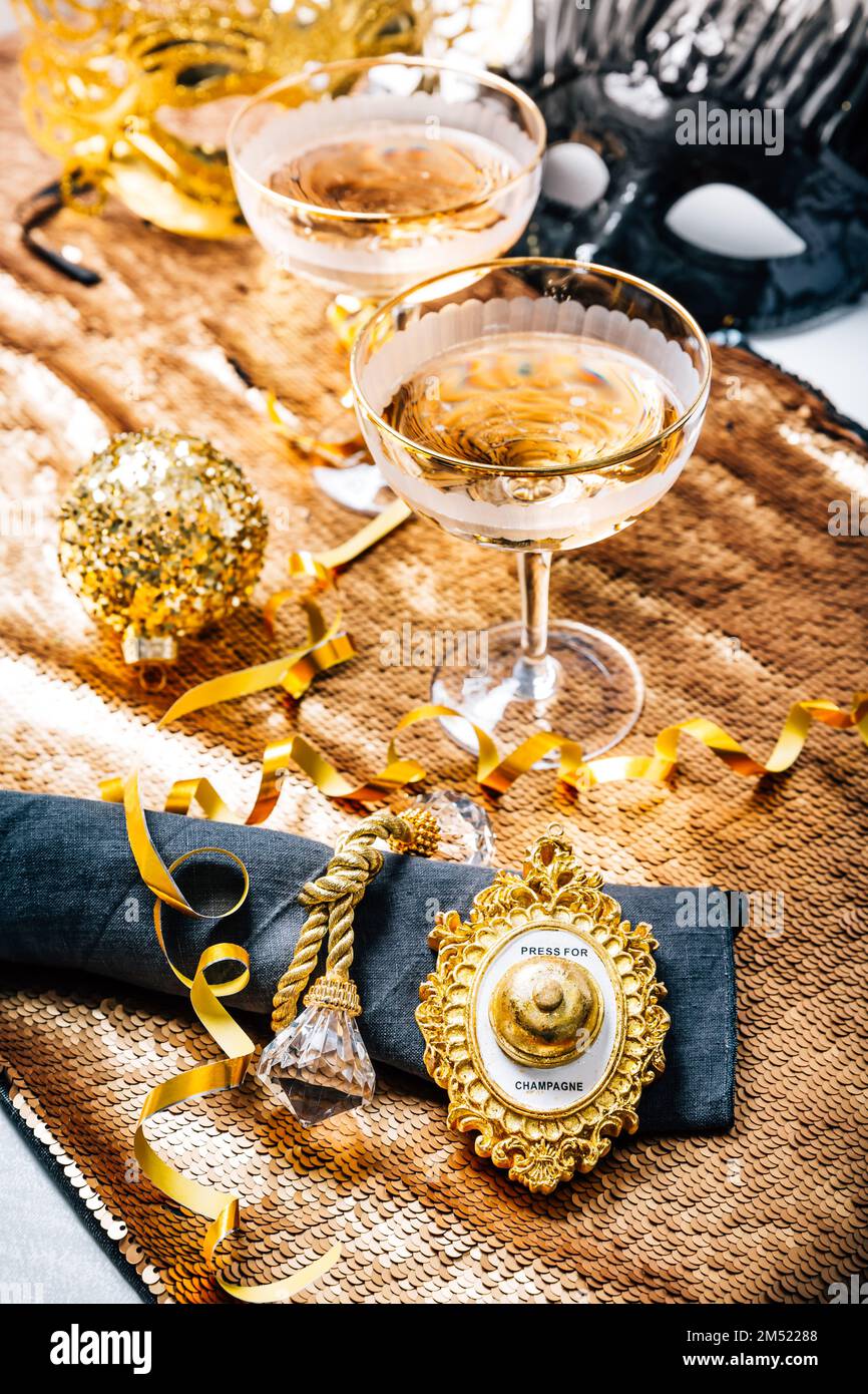 Two glasses of sparkling wine on festive table for New Year, party or carnival.  Bell push button for champagne, in golden tone Stock Photo