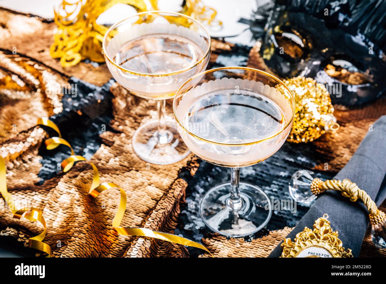 Two glasses of sparkling wine on festive table for New Year, party or carnival, in golden and black tone Stock Photo