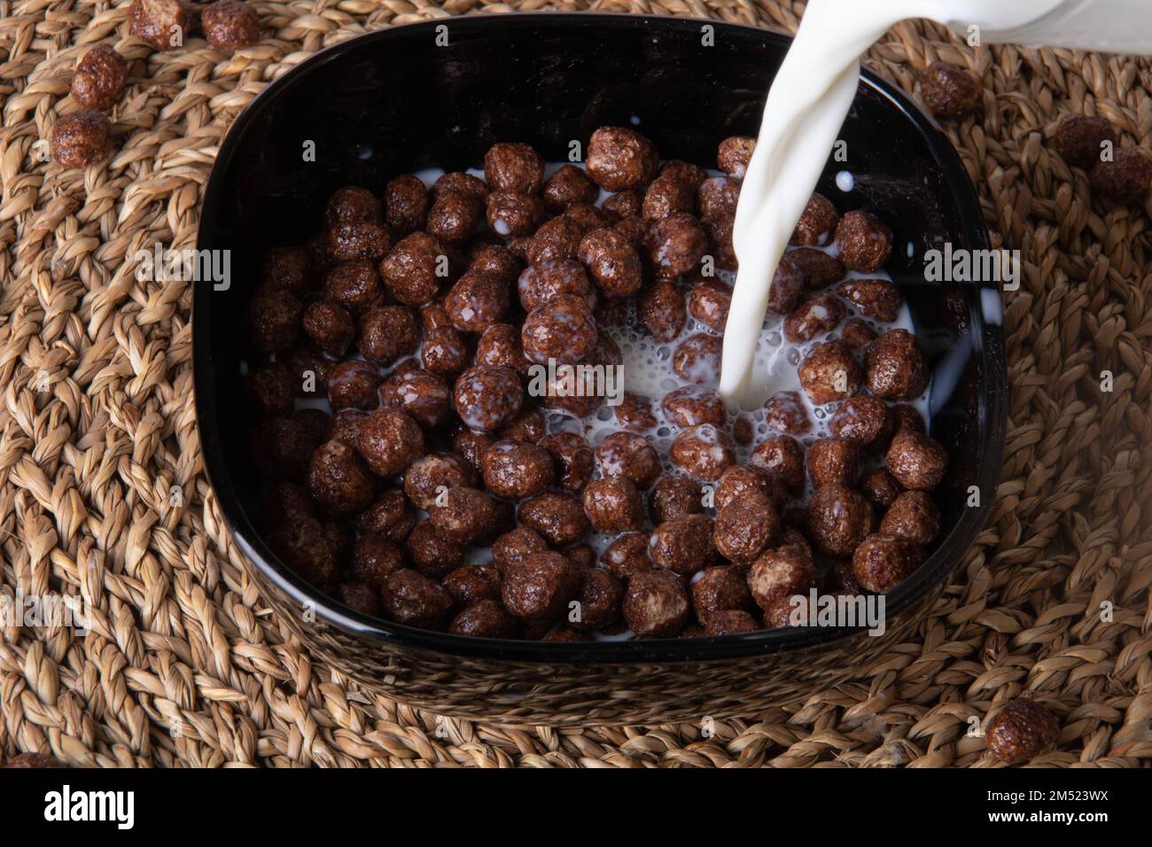 photo chocolate breakfast cereal balls floating in milk and pouring