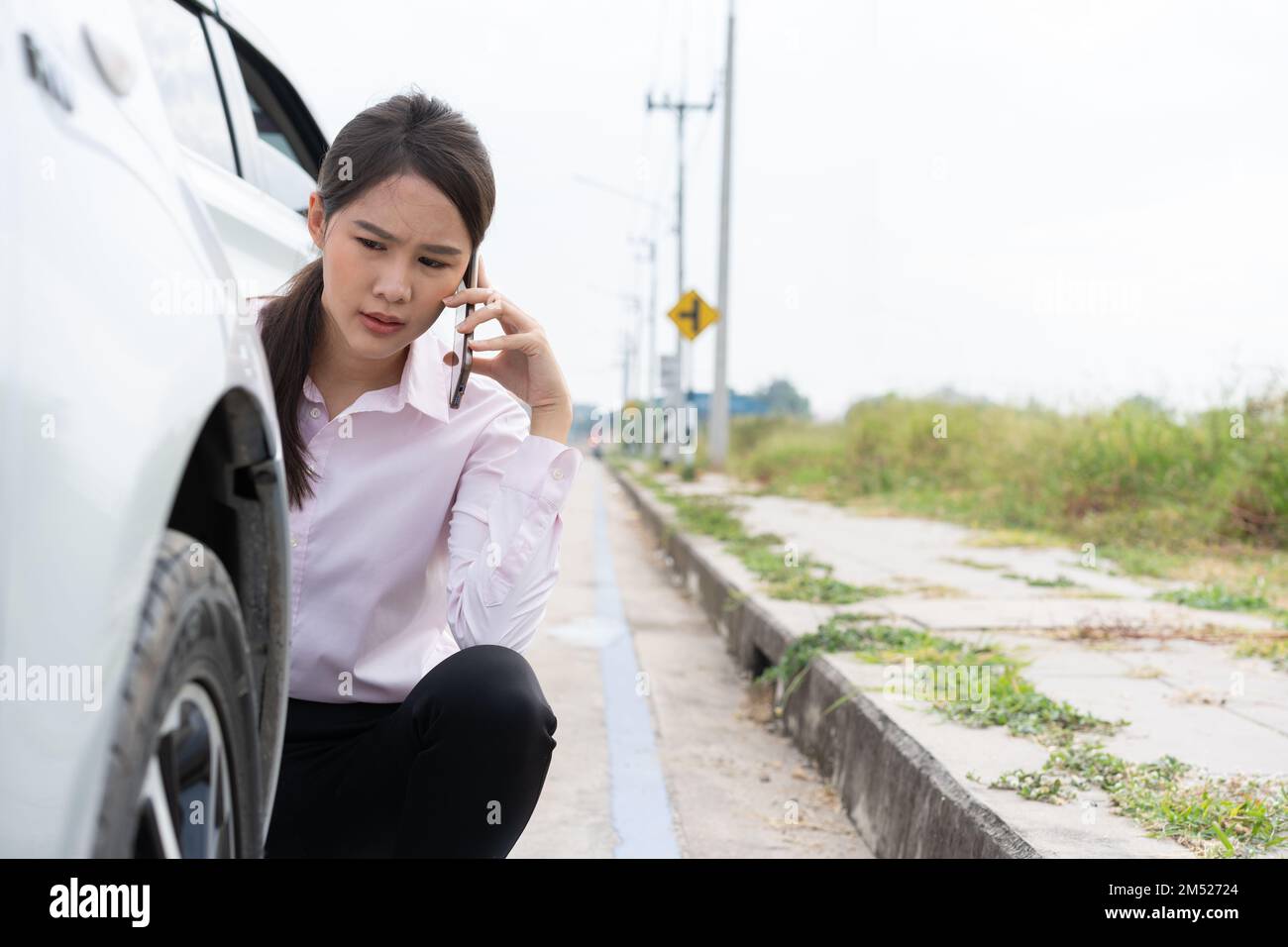 Asian women driver check for damage after a car accident before taking pictures and sending insurance. Online car accident insurance claim after submi Stock Photo