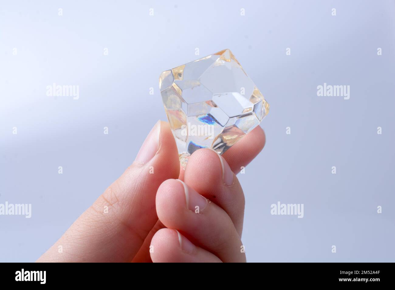 Hand holding a transparent diamond on a white background Stock Photo