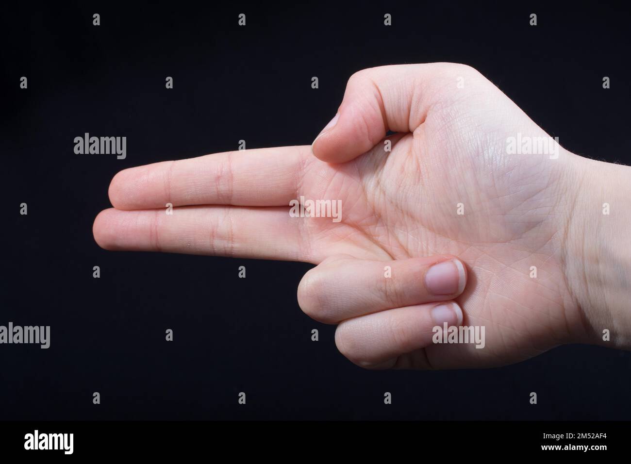 Hand gesture pointing fingers pistol-like handgun on black Stock Photo