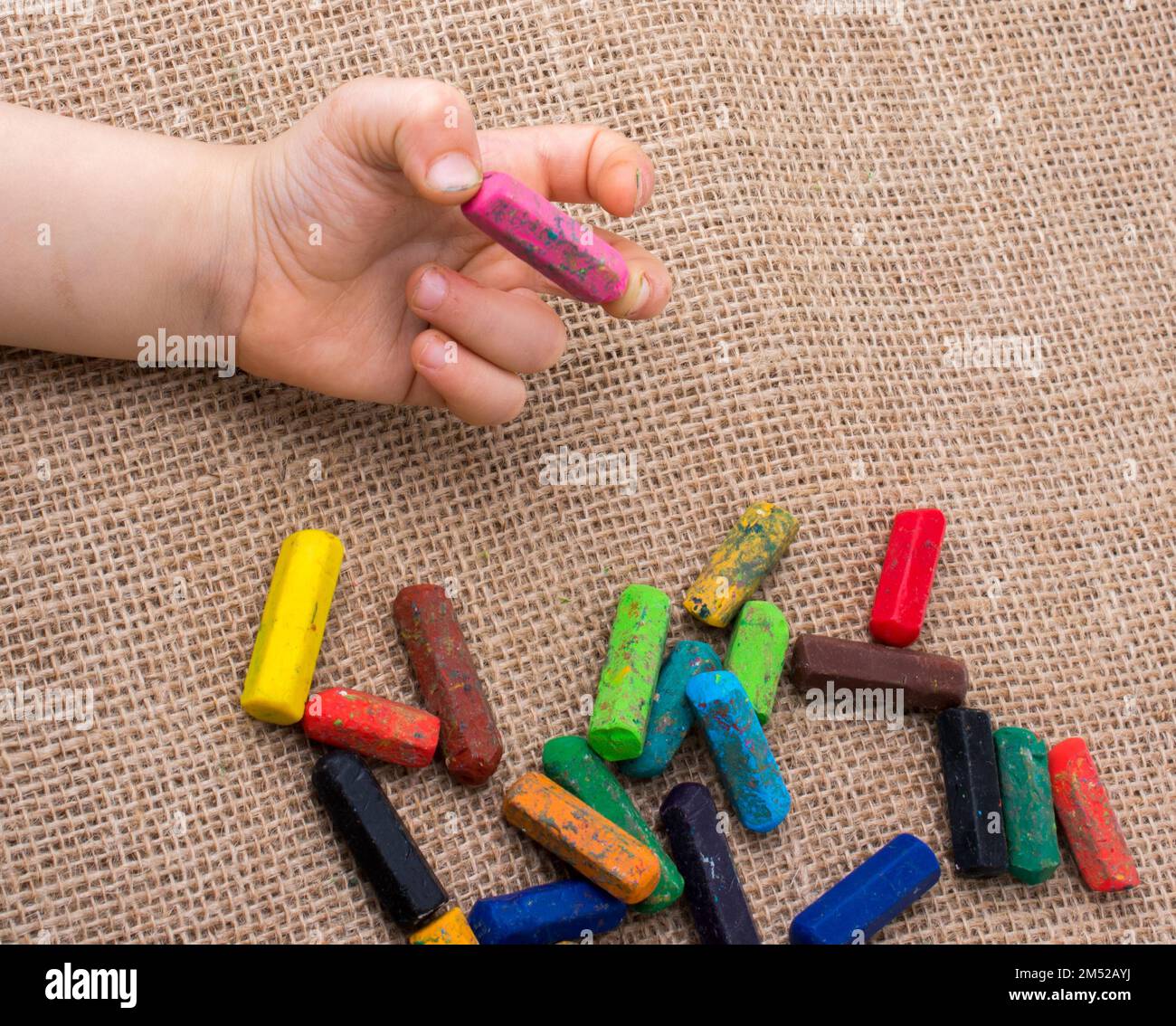 Used color crayons and a toddlers hand holding one Stock Photo Alamy