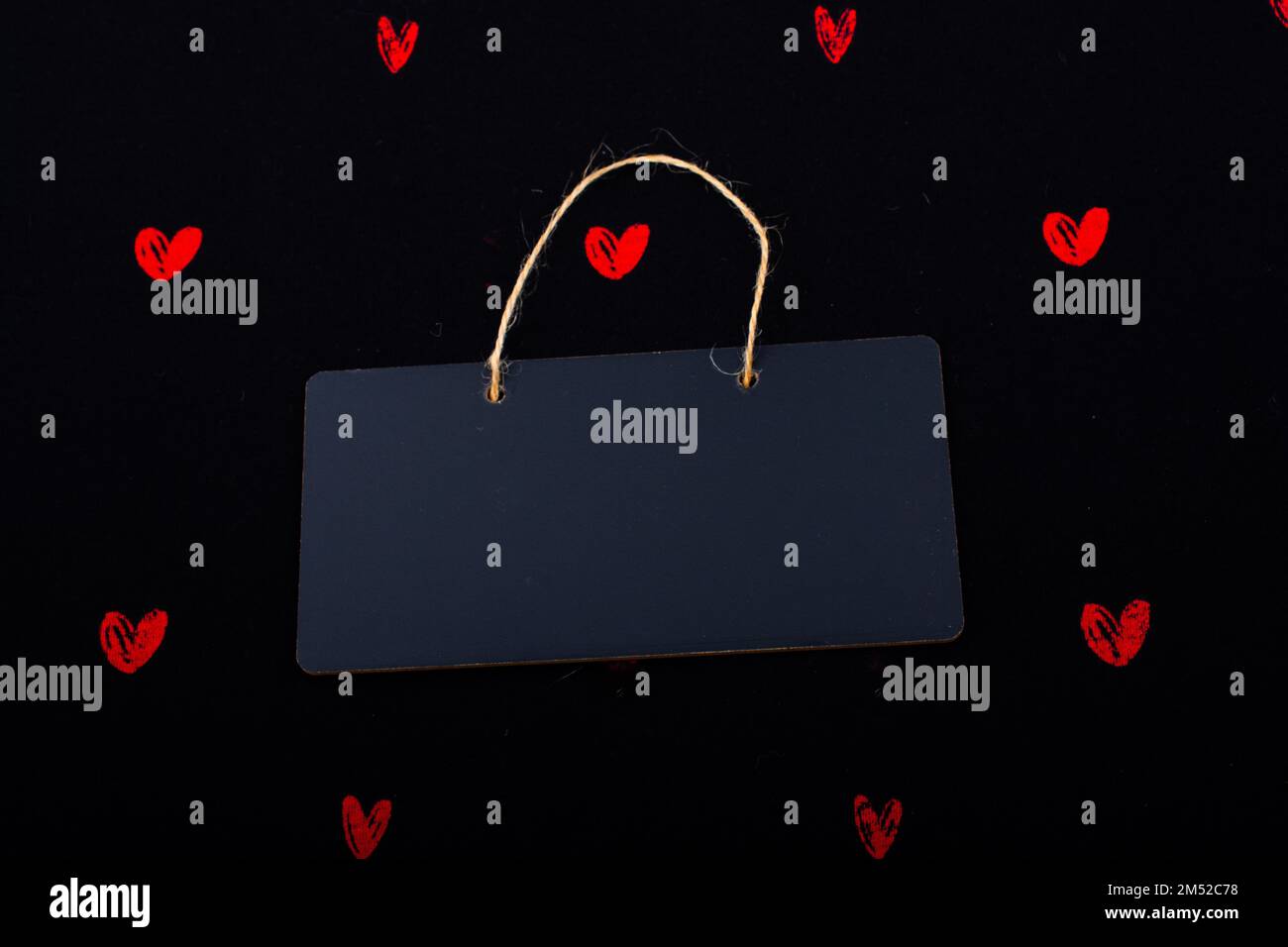 Rectangular shaped black notice board and red hearts on black background Stock Photo